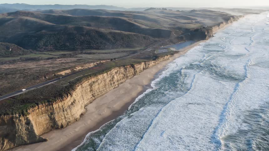 Aerial scenery of the sea on the coast with a highway in vehicle traffic one morning