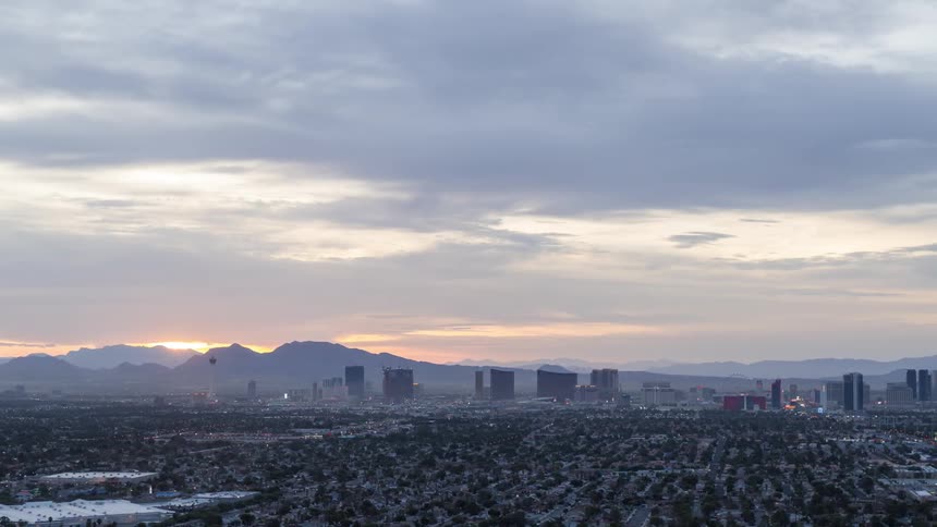 An aerial image of a city with many trees buildings and mountains in the background