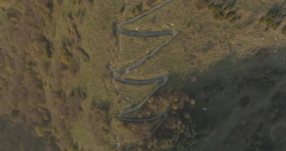 Aerial panorama of a greenish mountain with a winding path
