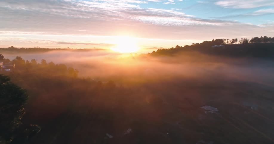 Footage of a landscape as the sun rises fog can be seen