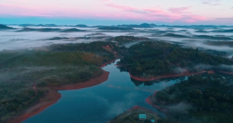 Aerial of a remote lake surrounded by a forest and hills at sunset
