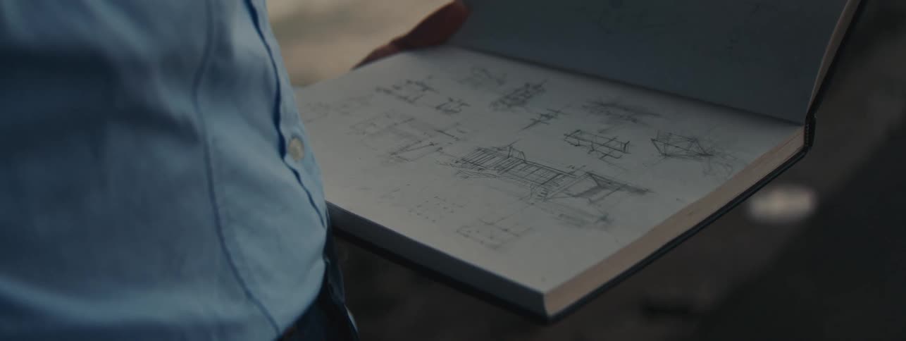 A person holding a sketch pad with drawings in it
