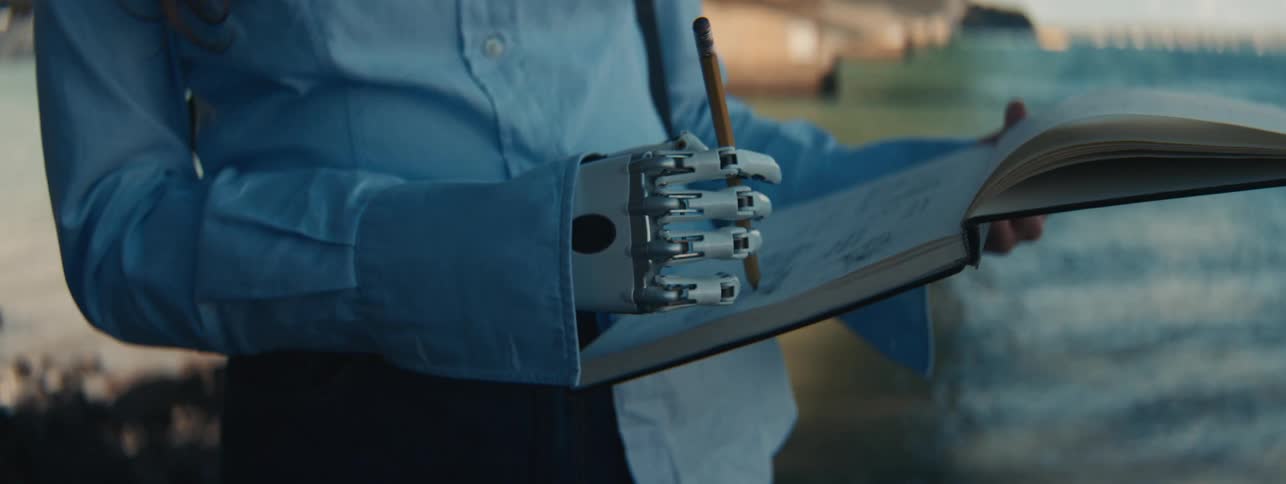 A woman with a prosthetic hand draws in a notepad