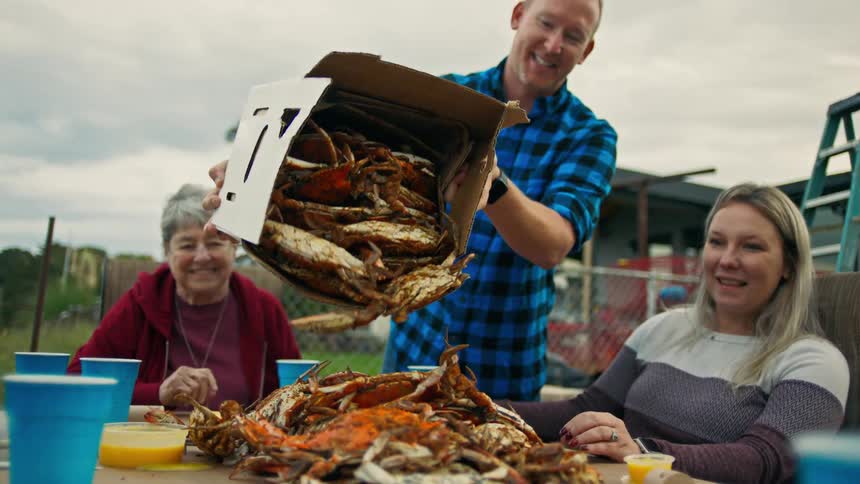 People sitting at a table and a man playing crabs at a table