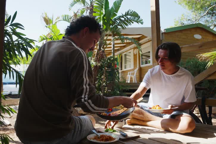 Two friends eat on a porch