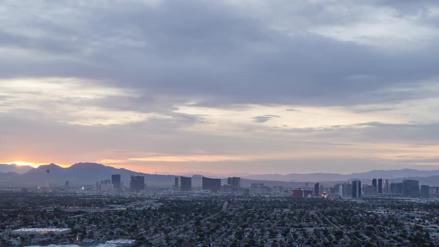 An aerial shot of a city skyline before distant peaks at dusk
