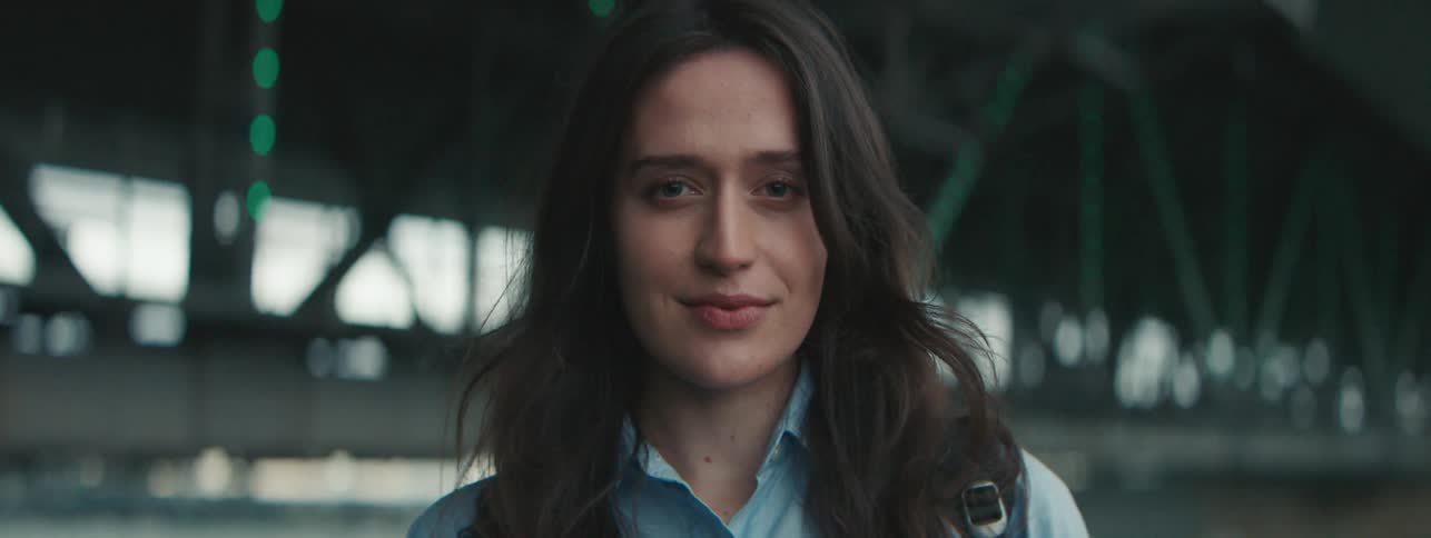 A woman standing near a bridge smiling