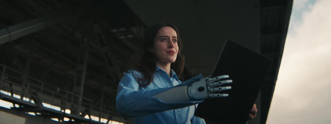 A woman with an artificial limb smiles while looking at a book