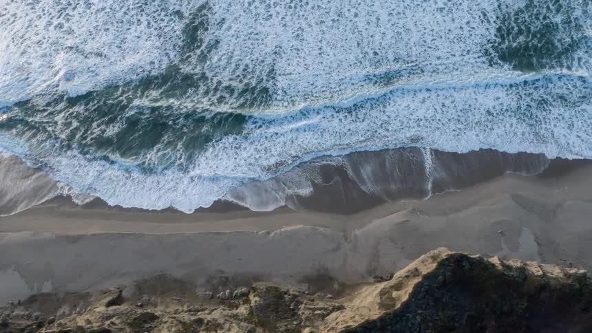 Birds eye view of waves rolling on to the sandy shoreline along the coast