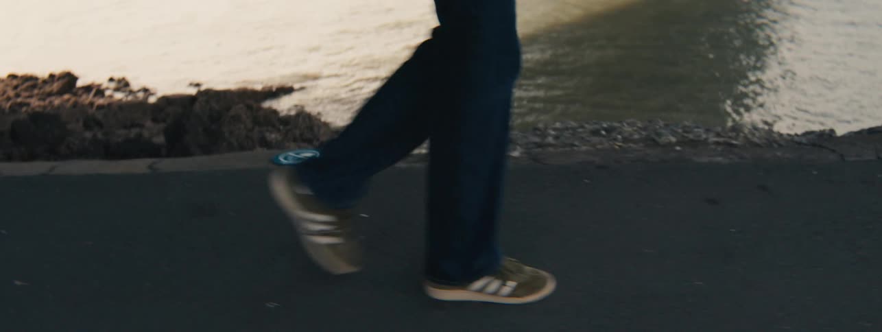 A person walks on a sidewalk next to a river