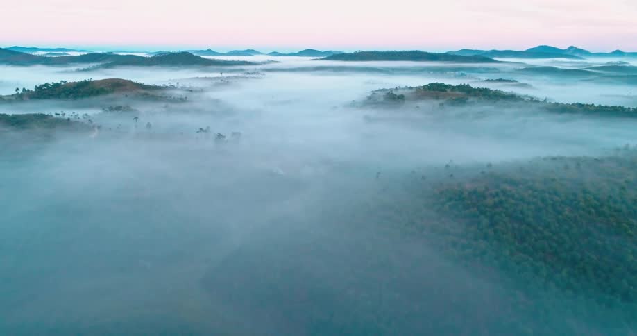 A dense fog hangs over mountains and forests