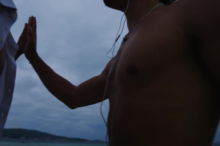 Two men in a natural setting holding their palms and looking at each other romantically