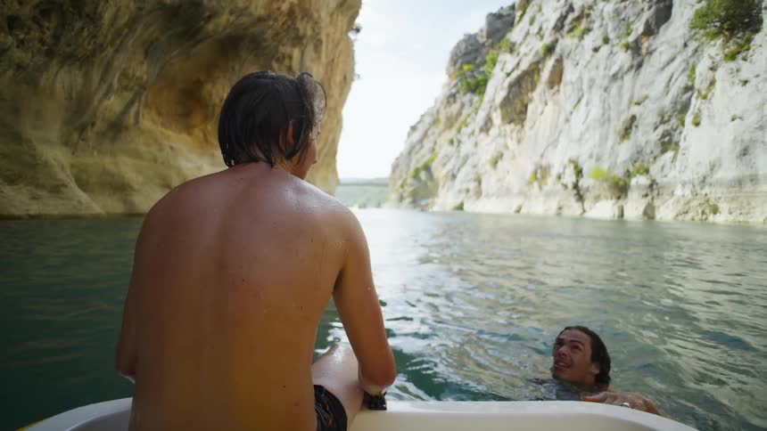 Two friends swimming in an archipelago and then getting on the boat and sitting back to back
