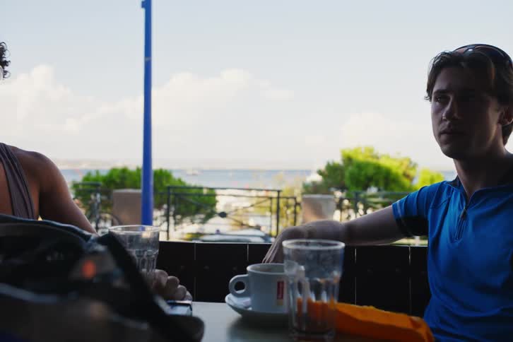 Four boys sitting at a table in a cafe drinking coffee and talking on the beach