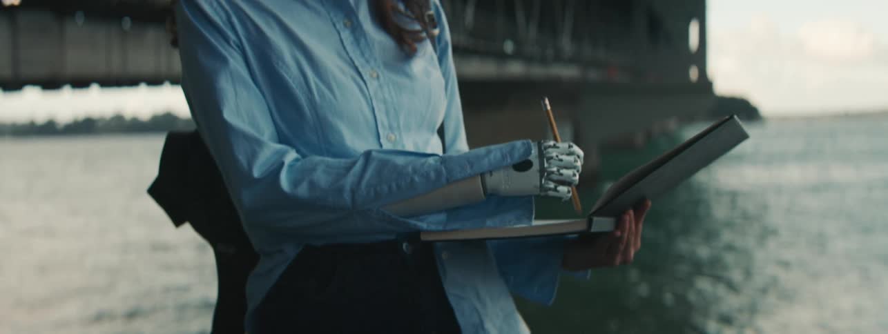 A woman with a metal hand draws in a book