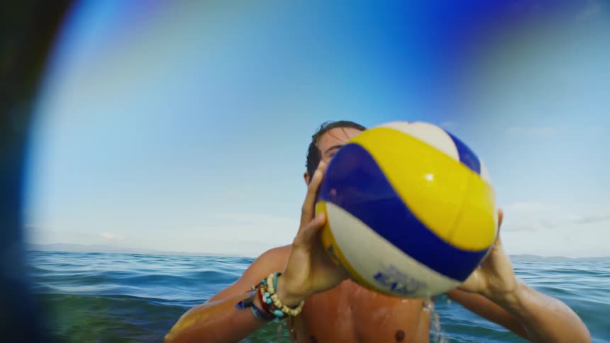 A young guy throws a ball around in the ocean
