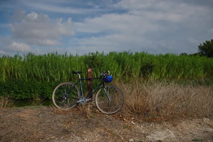 A bicyclist stands by a body of water