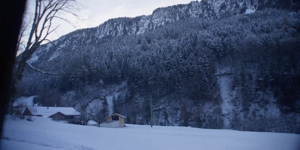 View from a window of a moving transport of wooded and snowcovered mountain ranges