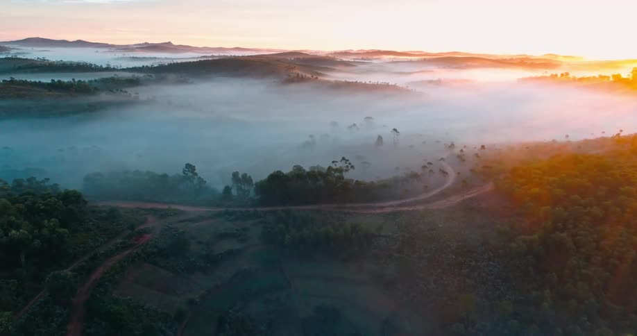 An aerial view of a region with a mountainous surface and a lot of fog