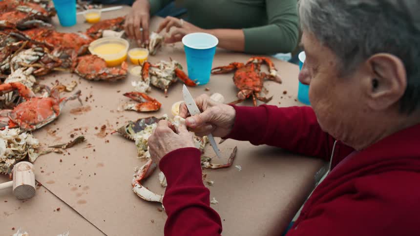 People sitting at a table peeling and eating crab