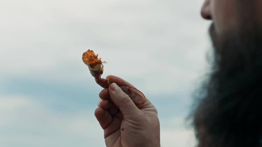 A bearded man examines a flower bud while talking to an older woman