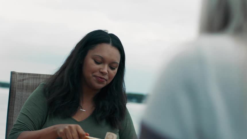 A young woman uses a small hammer to crack a shellfish shell