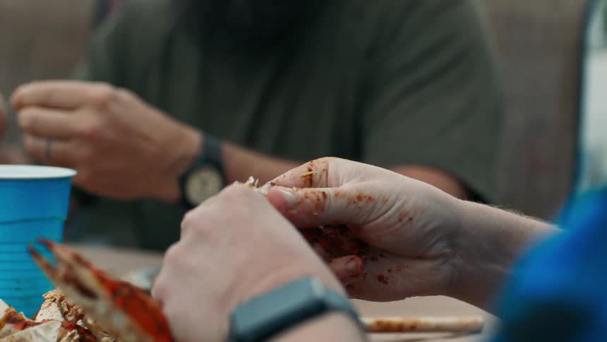 Hands of people breaking and eating crab