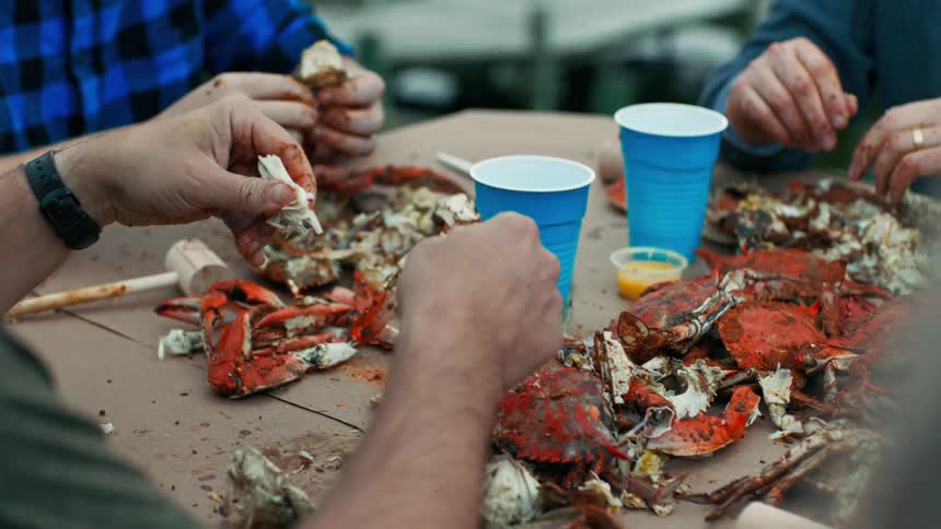 Hands of people sitting at a table eating crab