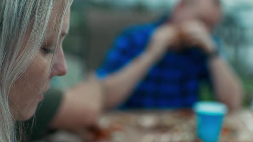 Side portrait of a woman sitting at a table with a blurred background and people eating