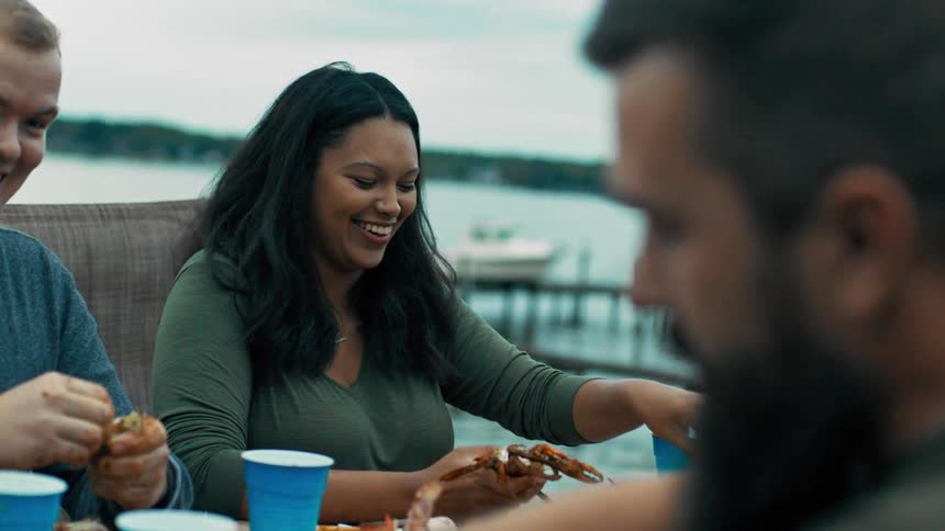 People sitting around a table near the sea eating large crabs