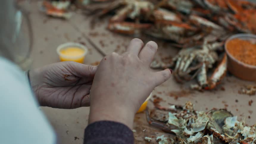 A woman is eating crab from the shell