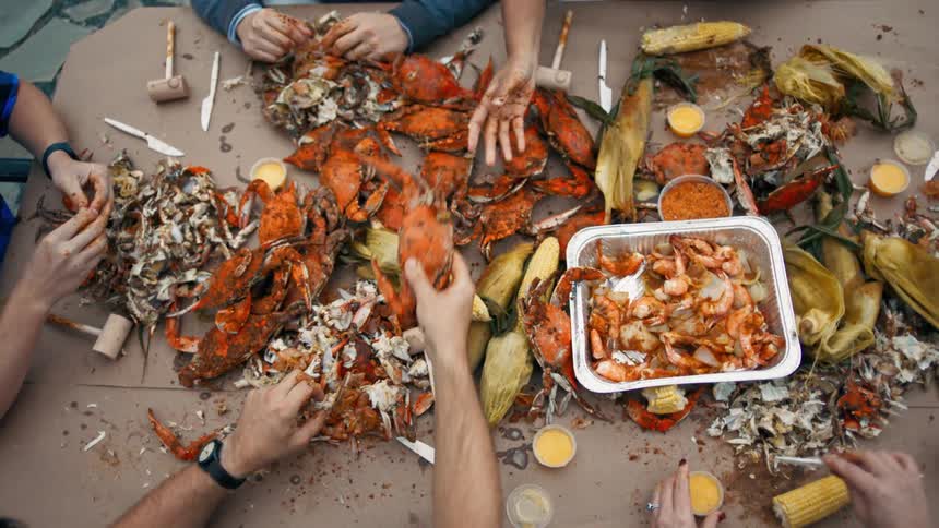 A group of people with a pile of seafood and corn