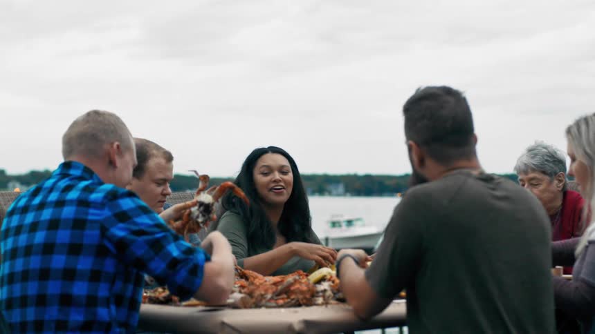 Group of freinds eating crab outsdoors near the the lake