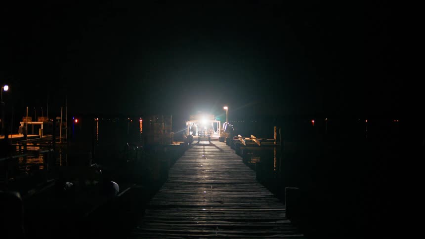 A person moves around a lit up boat at a dock