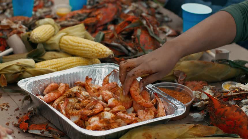 People sitting around a table and eating shrimp and corn