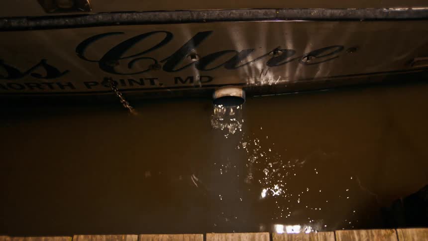 Boat exhaust releasing water into the sea at night