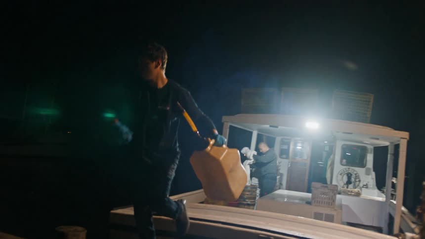 Two commercial fisherman working on and off a boat