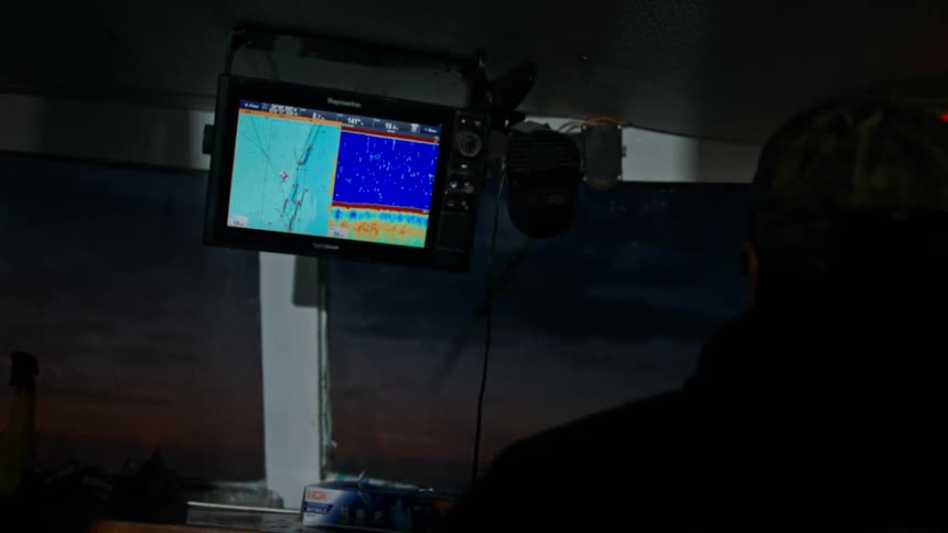 A fisherman pilots a boat on an ocean