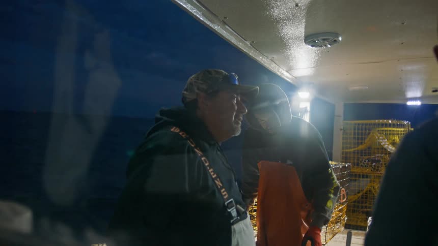 Three men are in a cabin on a boat because it has a strong light and they are sailing on the sea one night
