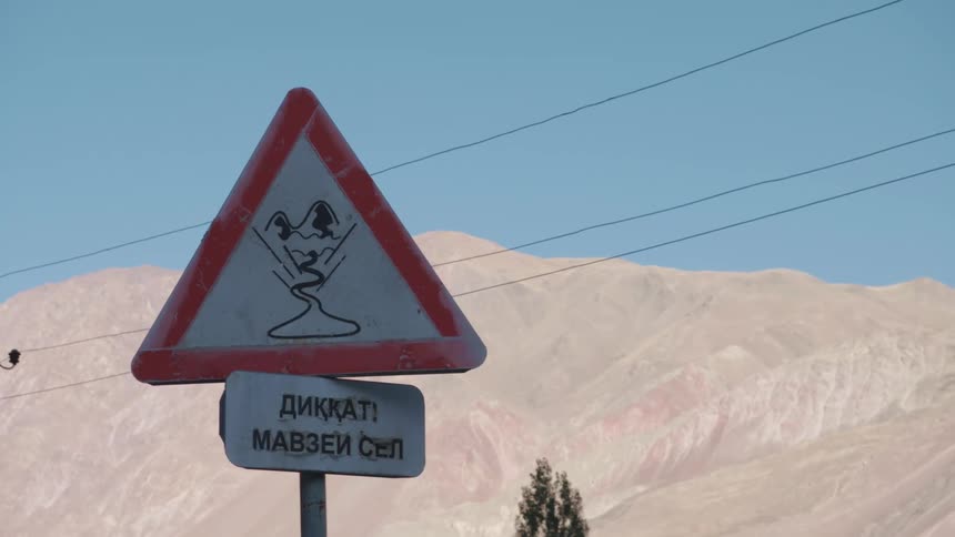 Warning signpost in a natural environment with rocky mountains around
