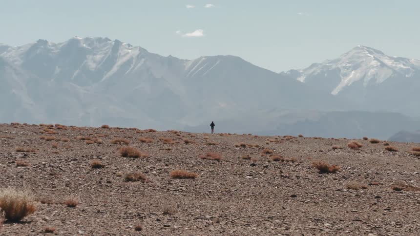 Landscape of a person running in a natural environment amidst mountains on a clear day with few clouds