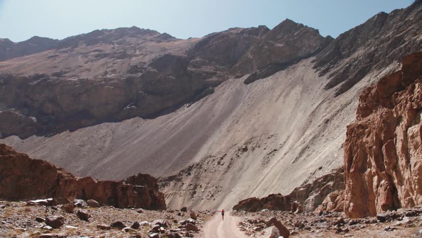 Mountains and canyon during the day with a person running