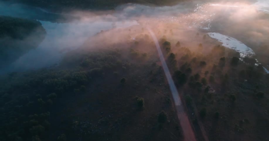 Aerial panorama of a dirt road in hills and near lakes on a morning