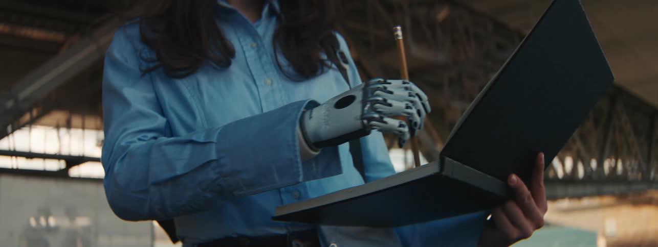 A woman with a prosthetic hand draws on a pad