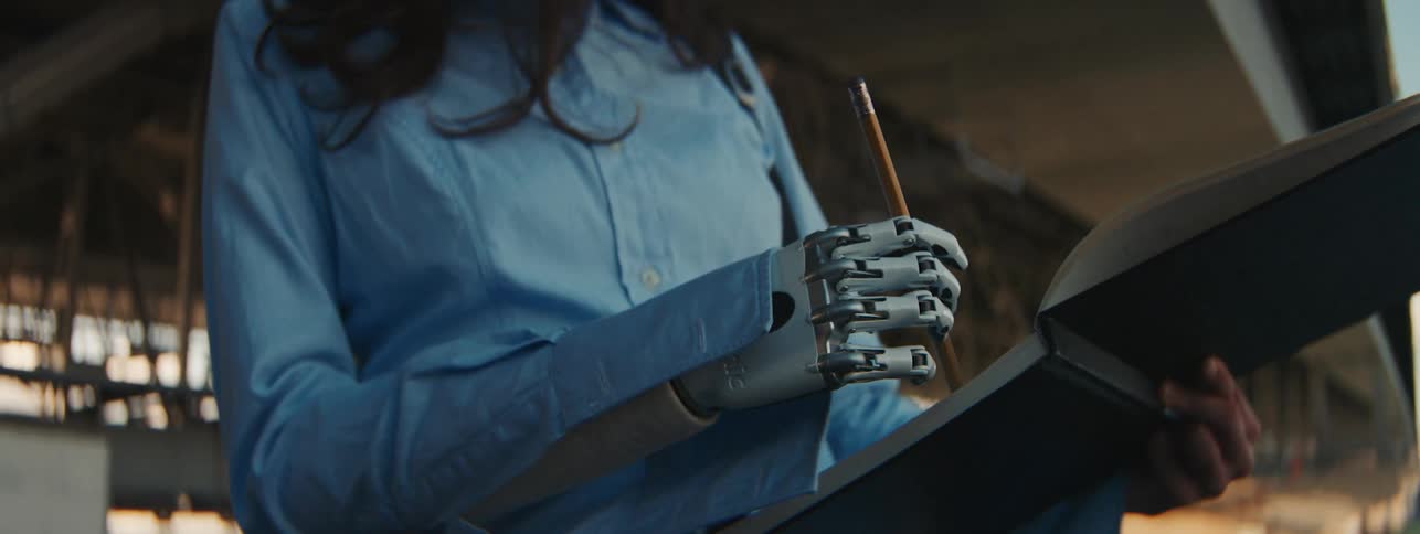 A woman with a prosthetic hand draws in a notepad