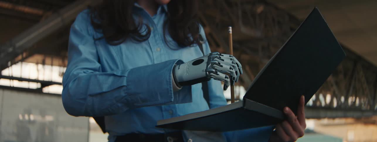 Woman holding a laptop with one of her robotic hands