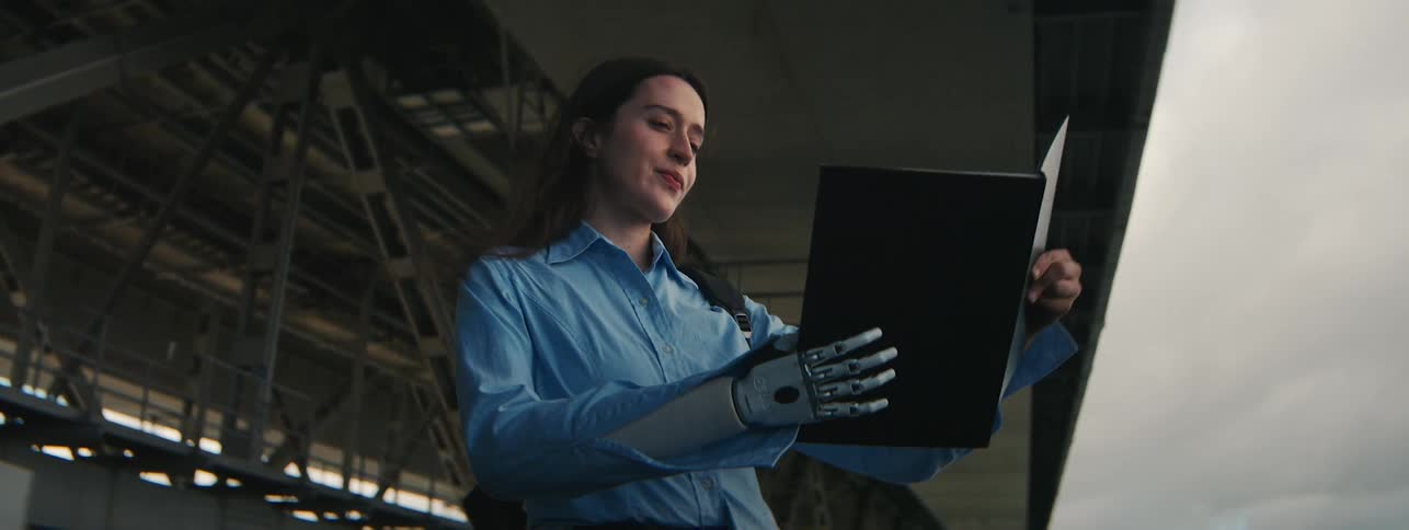 Woman in outdoor environment holding a folder with one of their robotic hands