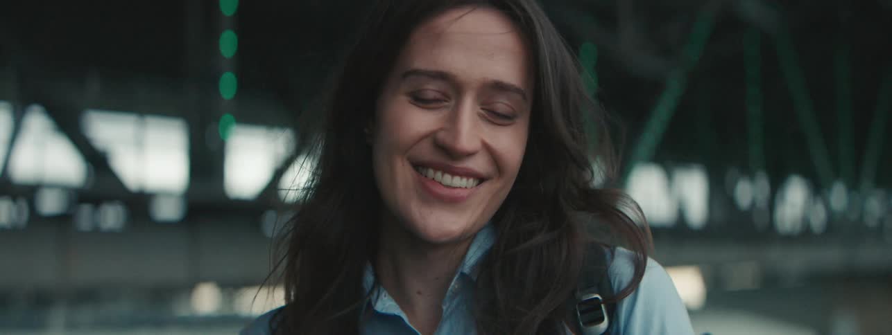 A young woman smiles near a bridge