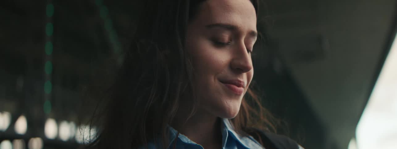 Portraits of a young woman smiling slightly while her hair moves with the force of the wind