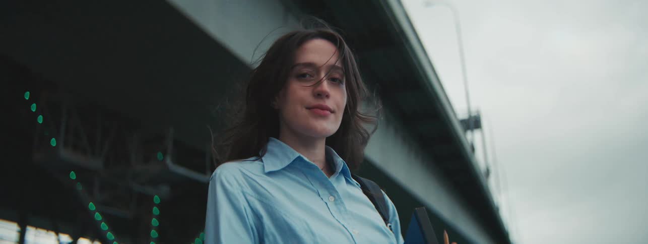 A woman with dark hair poses while standing under an overpass